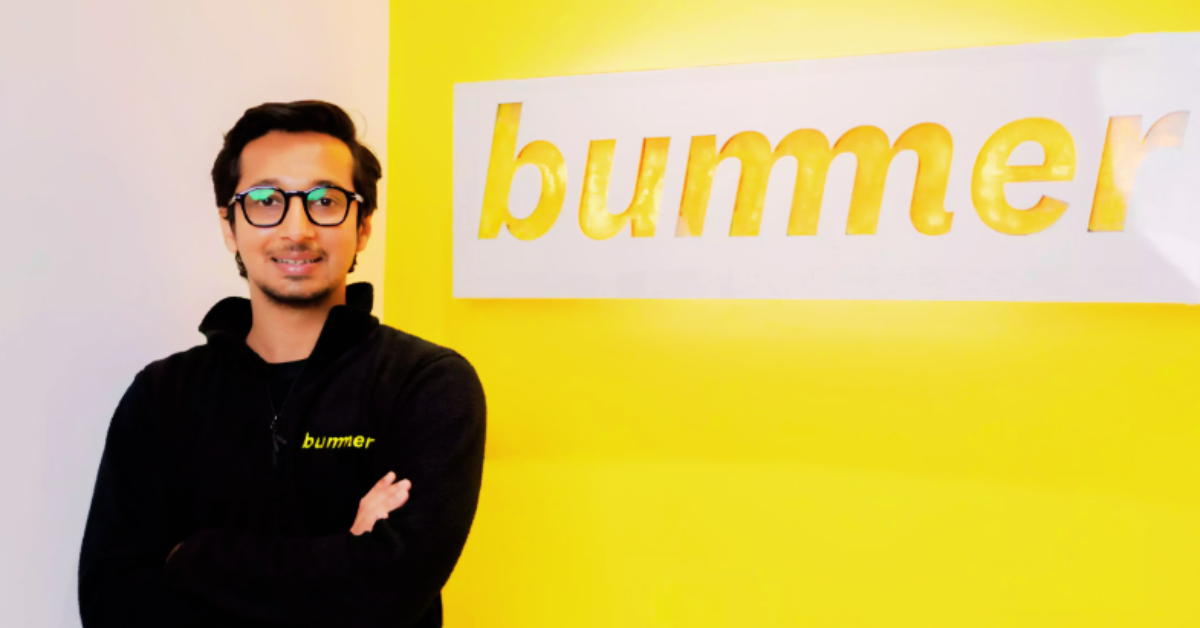 Man in glasses standing beside a yellow wall with the word "bumble" in lowercase letters.