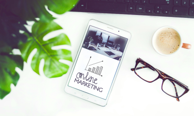 A tablet displaying 'online marketing' graphics placed on a desk beside a cup of coffee and a pair of eyeglasses.